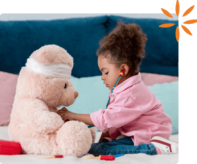 Child pretending to examine a teddy bear with a toy stethoscope.
